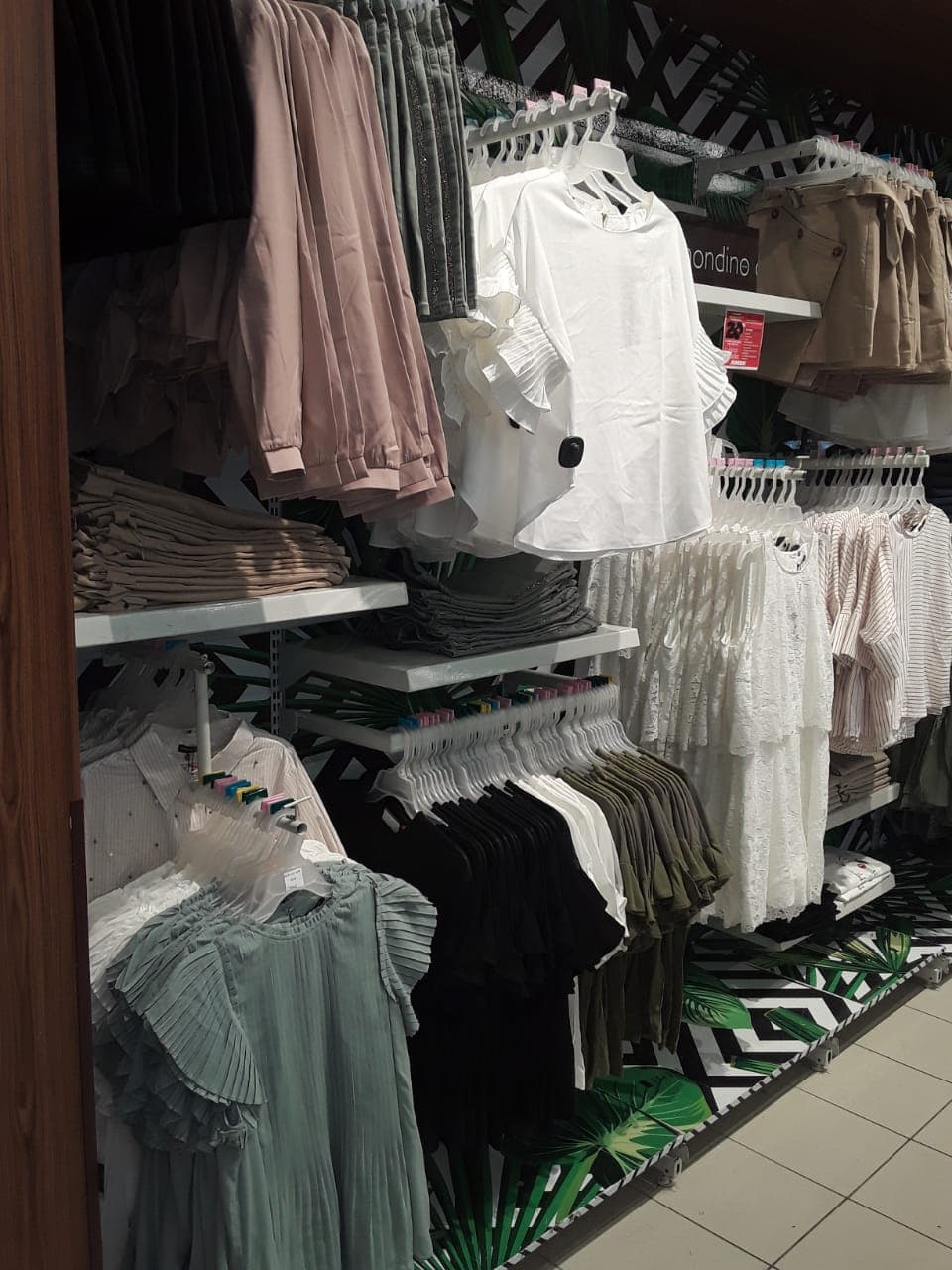Side angle of Mondino womenswear wall — multi-level hanging and folding